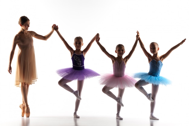 Três pequenas bailarinas dançando com professor de balé pessoal no estúdio de dança
