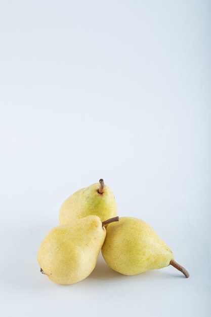 Foto grátis três peras amarelas em branco.
