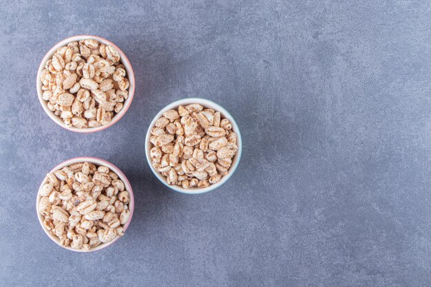 Três tigelas de muesli doce, na mesa de mármore.