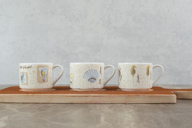 Foto grátis três xícaras de café na placa de madeira.