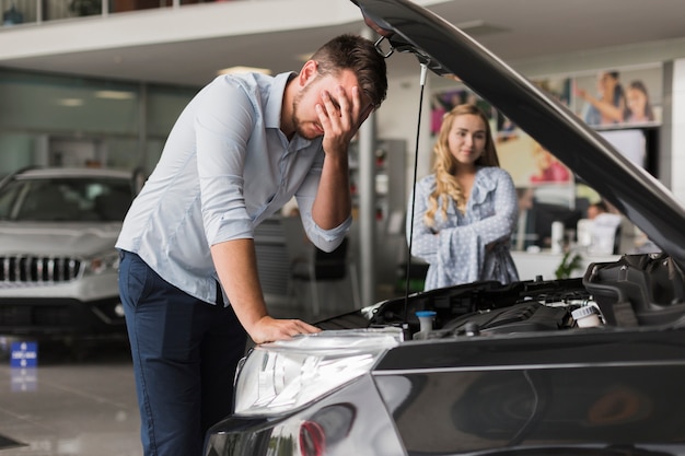 Triste homem inspecionando o motor do carro