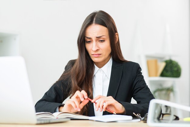 Triste, jovem, executiva, segurando, lápis vermelho, em, dela, sentando, em, escrivaninha escritório