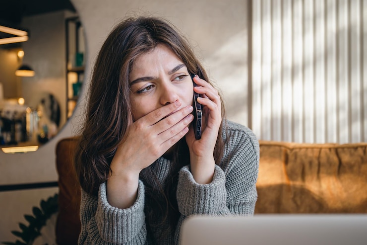 Foto grátis triste jovem falando ao telefone enquanto está sentado na frente de um laptop