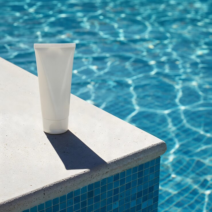 Foto grátis tubo de protetor solar ao lado de uma piscina azul brilhante