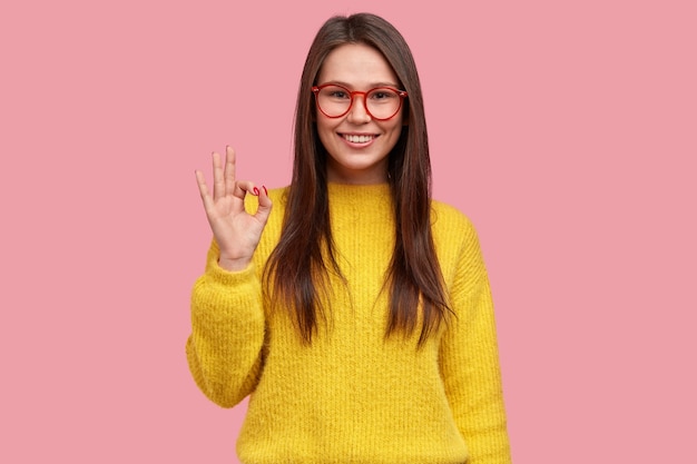 Tudo está bem e sob controle. Mulher feliz e positiva mostra um gesto de aprovação e demonstra aprovação da ideia