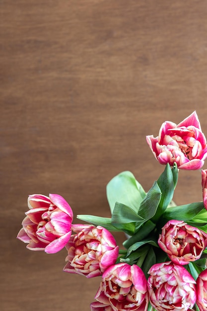 Tulipas frescas cor-de-rosa em uma mesa de madeira