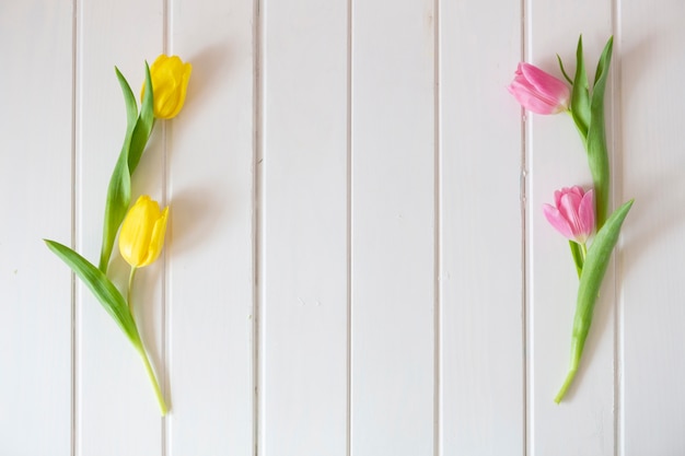 Foto grátis tulipas rosa e amarelo na superfície de madeira