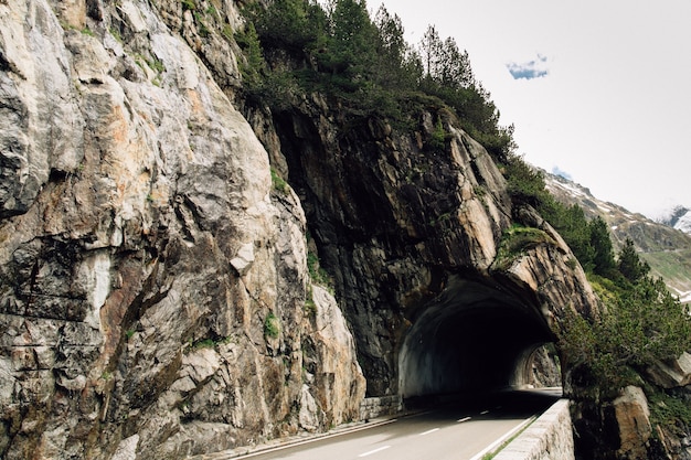 Túnel do carro em rocha na estrada no alto dos Alpes suíços