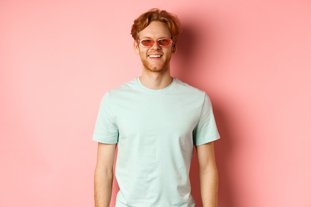 Turismo e férias conceito ruiva alegre barbudo homem em óculos escuros e camiseta sorrindo e olhe ...