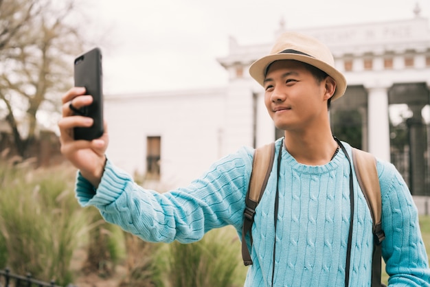 Turista asiática tirando uma selfie com o celular.