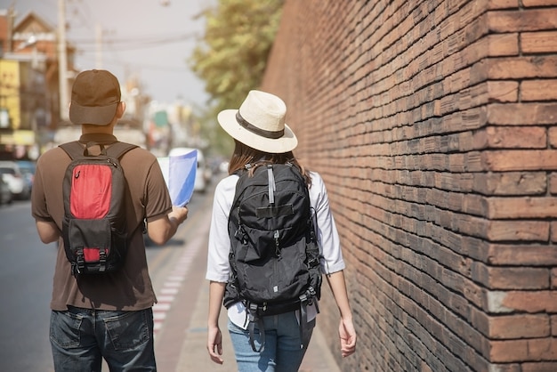 Turista de casal asiático segurando o mapa da cidade atravessando a estrada