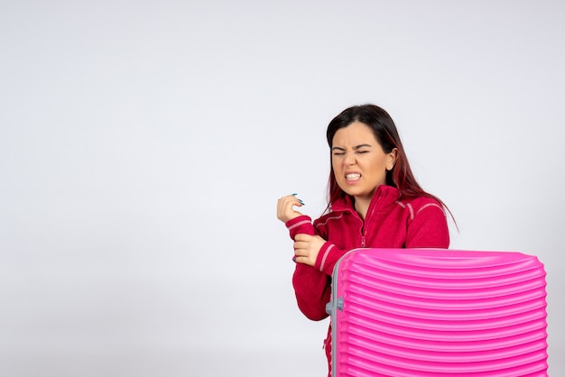 Turista de frente com bolsa rosa machucou o braço na parede branca