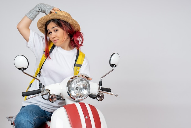 Turista de frente para mulher sentada e posando em uma motocicleta na parede branca