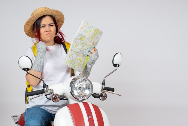 Turista de frente para mulher sentada em uma motocicleta com a parede branca do mapa