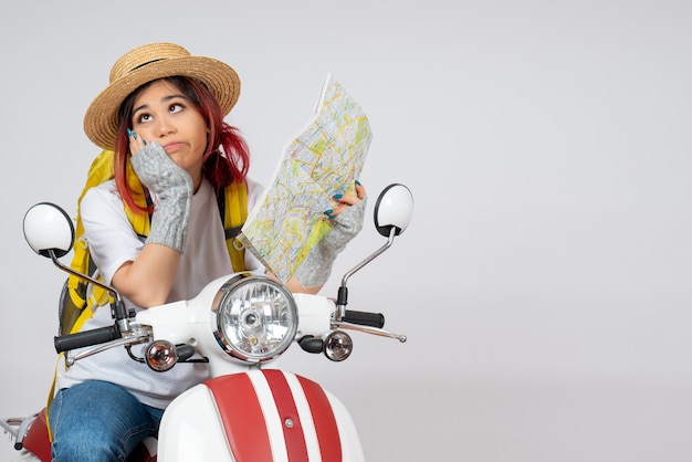 Turista de frente para mulher sentada em uma motocicleta segurando uma parede branca do mapa