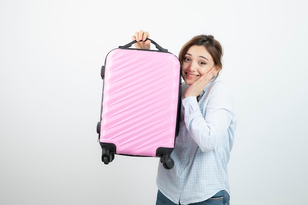 Turista de mulher em pé e segurando a mala de viagem rosa. Foto de alta qualidade