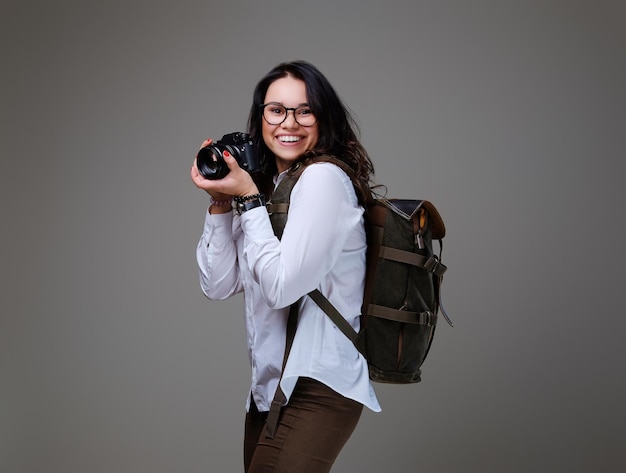 Turista feminina positiva com câmera fotográfica e mochila de viagem.