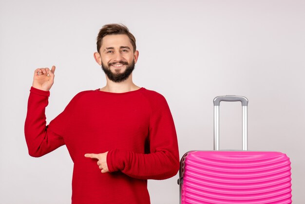 Turista masculino de frente com bolsa rosa na parede branca