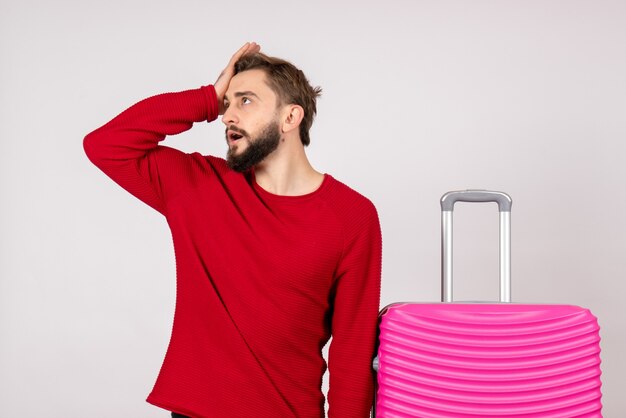 Turista masculino de frente com bolsa rosa na parede branca