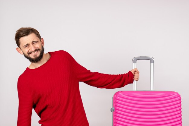 Turista masculino de frente com bolsa rosa na parede branca