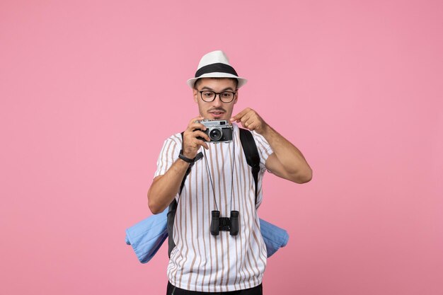 Turista masculino tirando fotos com a câmera na parede rosa turista cor de rosa