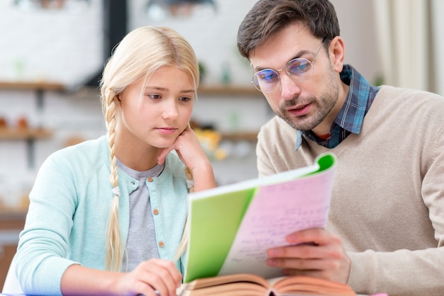 Tutor e menina em casa lendo do caderno