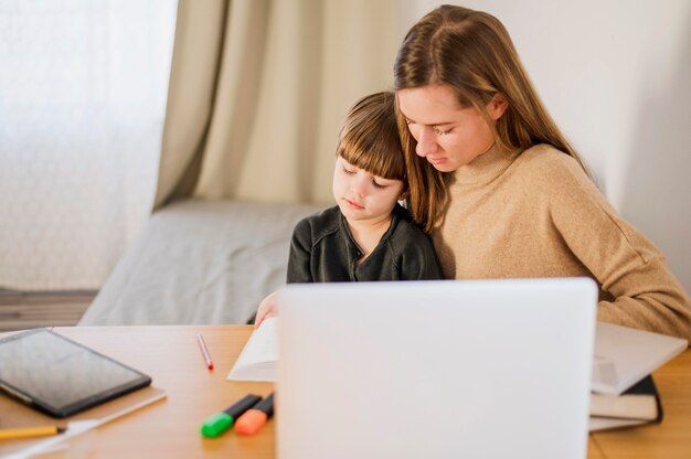 Tutor feminino, ensinando a criança em casa com o laptop