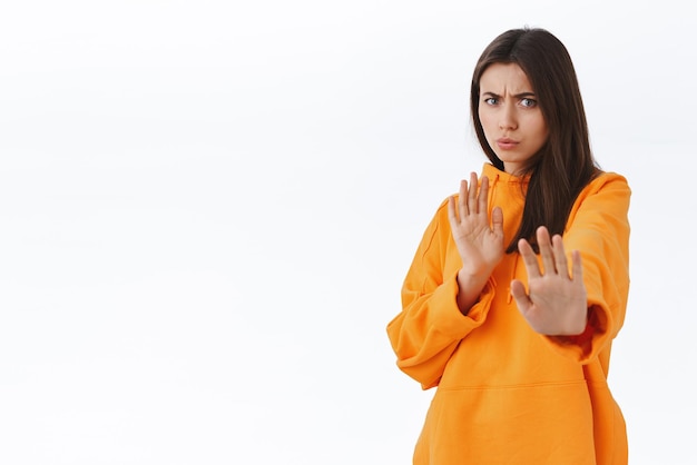 Foto grátis ugh yuck mulher jovem feminina enojada e relutante dizendo por favor, pare de franzir a testa e fazer caretas de desaprovação e aversão, não gosta de oferecer um passo para trás recusando proposta fundo branco