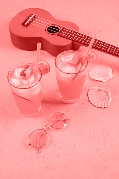 Foto grátis ukulele; taças de cocktail; conchas de vieiras e óculos de sol em fundo coral