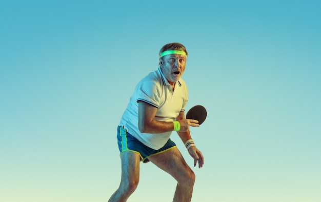 Último homem jogando tênis de mesa em uma parede gradiente com luz de néon