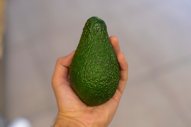 Um abacate verde na mão de uma pessoa