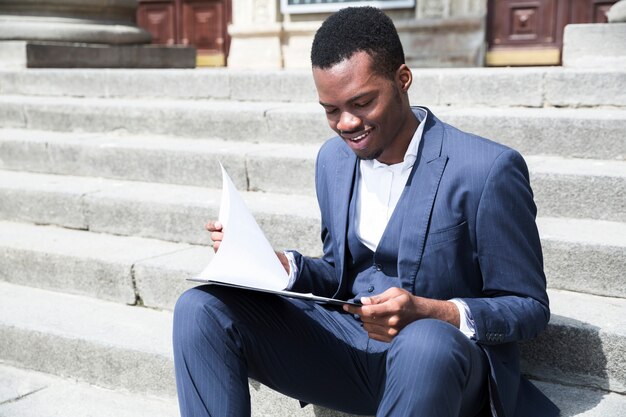 Um, africano, jovem, homem negócios, falando telefone móvel, sentando, ligado, escadaria, com, laptop