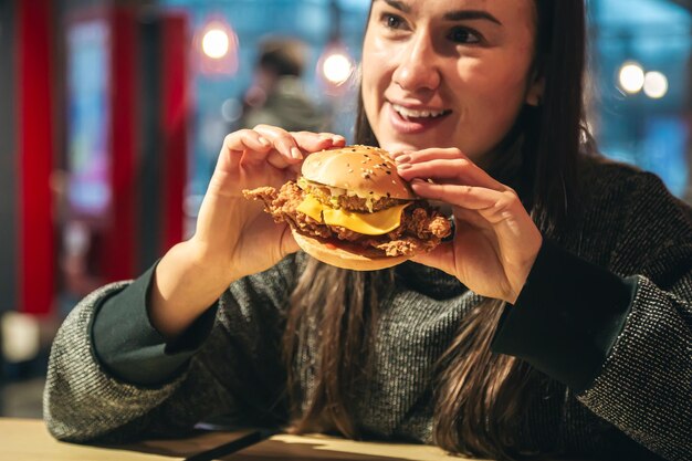 Foto grátis um apetitoso hambúrguer de frango em mãos femininas em um restaurante fast food