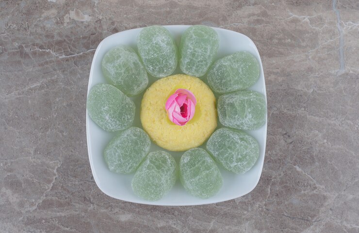 Foto grátis um arranjo de marmeladas, um biscoito e uma corola de flor em uma travessa sobre mármore