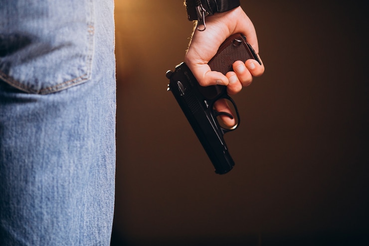 Foto grátis um ator bonito posando no estúdio com uma arma.