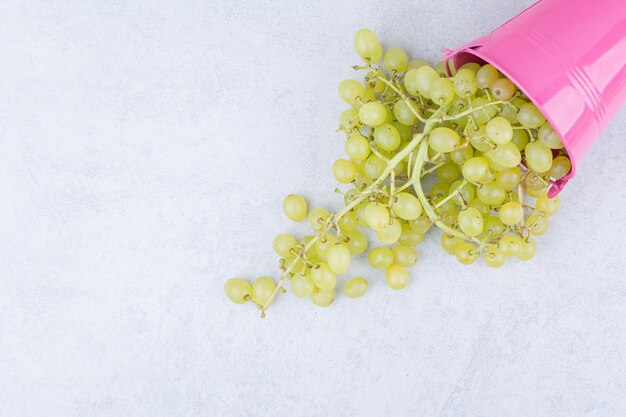 Um balde rosa cheio de uvas verdes doces. Foto de alta qualidade