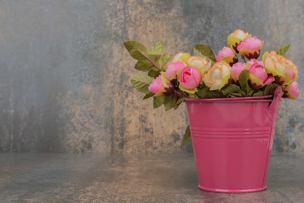 Foto grátis um balde rosa com buquê de flores na superfície de mármore.