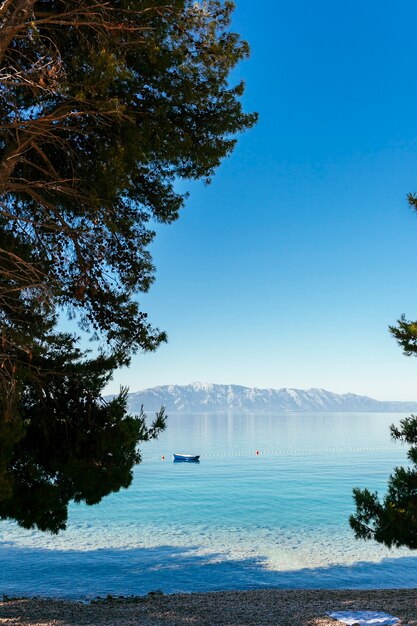 Um barco solitário flutuando no lago com a montanha na distância contra o céu azul claro