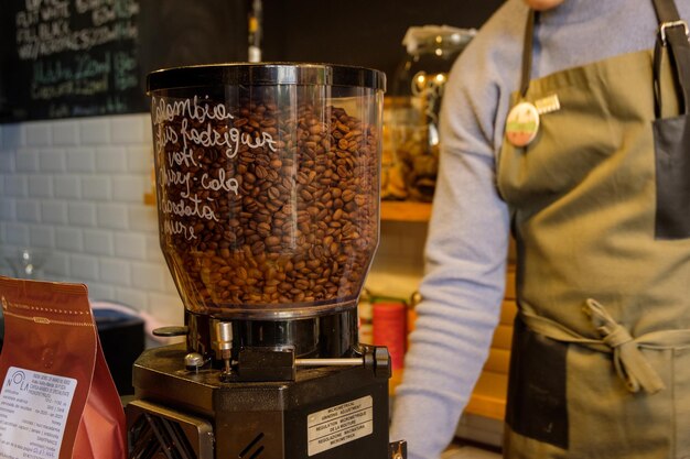 Um barista perto de um copo de grãos de café na cafeteria ambiental da máquina de café preto