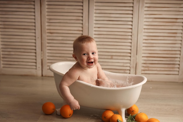 Um Bebe Alegre De 9 Meses Tomando Banho Em Uma Banheira De Bebe Branca Com Laranjas Foto Premium