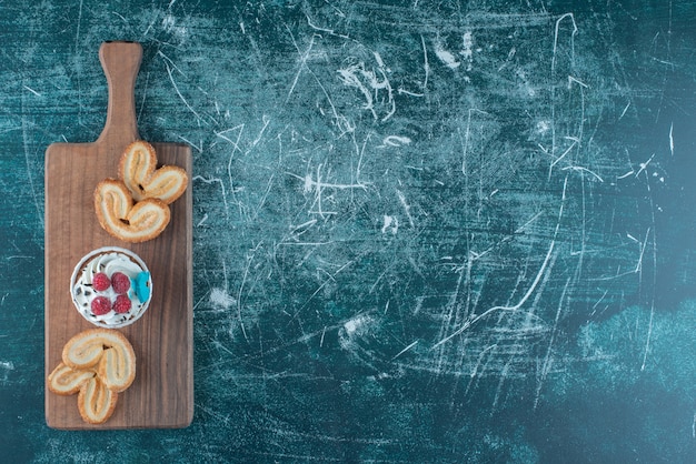 Um bolinho e biscoitos escamosos agrupados em uma placa sobre fundo azul. Foto de alta qualidade