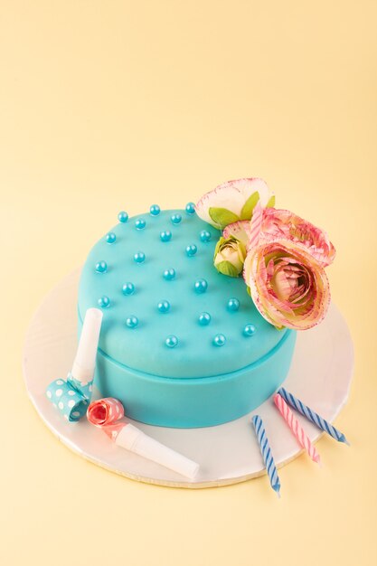 Um bolo de aniversário azul com uma flor no topo e velas coloridas