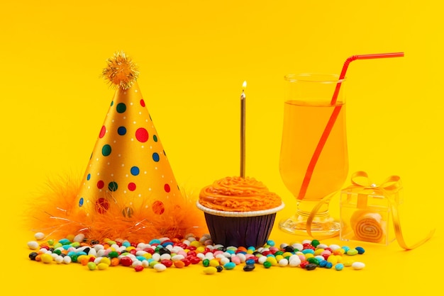 Foto grátis um bolo de aniversário com vela e doces coloridos e uma tampa de aniversário em um biscoito doce de cor amarela