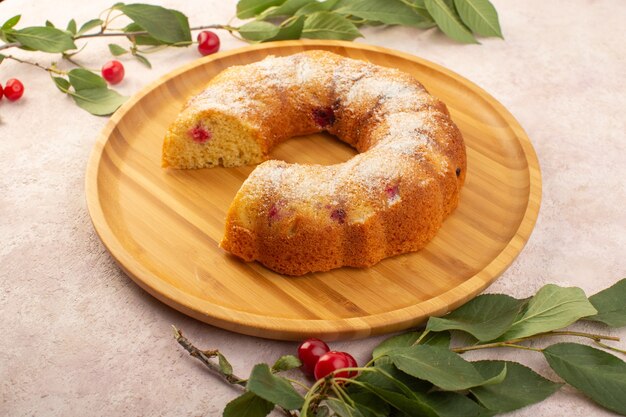 Um bolo de cereja frontal na mesa de madeira com cerejas frescas na mesa rosa