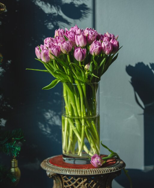 Um buquê de tulipas cor de rosa com folhas verdes dentro de um vaso