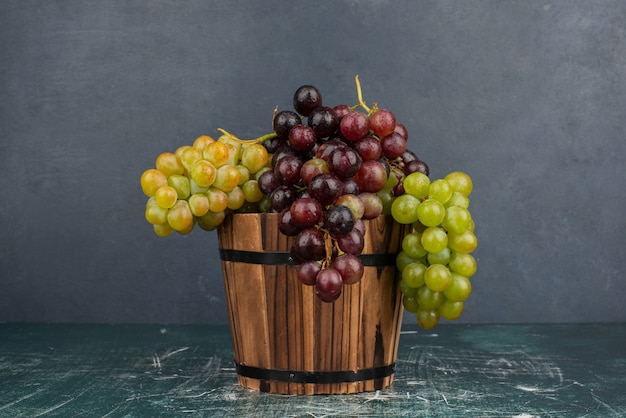 Um cacho de uvas verdes e pretas na mesa de mármore.