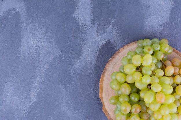 Foto grátis um cacho de uvas verdes na bandeja de madeira.