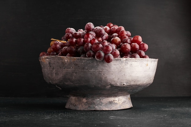 Um cacho de uvas vermelhas em uma tigela metálica.