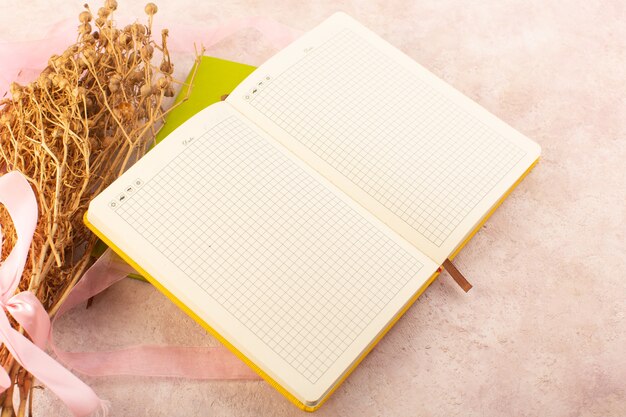 Um caderno vazio com planta de peganum harmala na mesa rosa estudar a planta caneta de aprendizagem