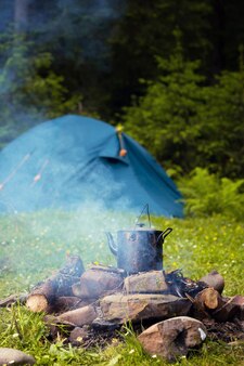 Um caldeirão na fogueira e uma tenda ao fundo